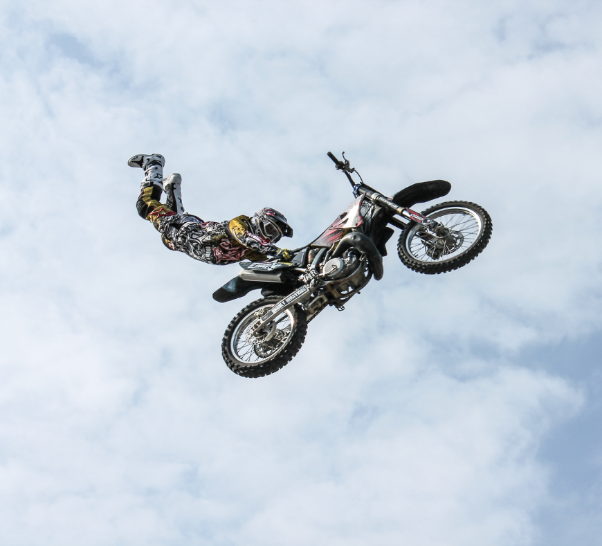 A high-energy FMX stunt, showcasing a rider soaring through the air while executing an adrenaline-pumping freestyle motocross trick.