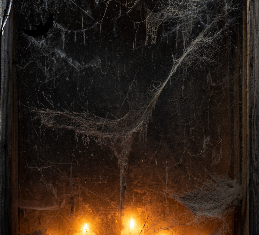 An old mirror covered in cobwebs, with flickering candles in front casting an eerie reflection off the dusty glass.
