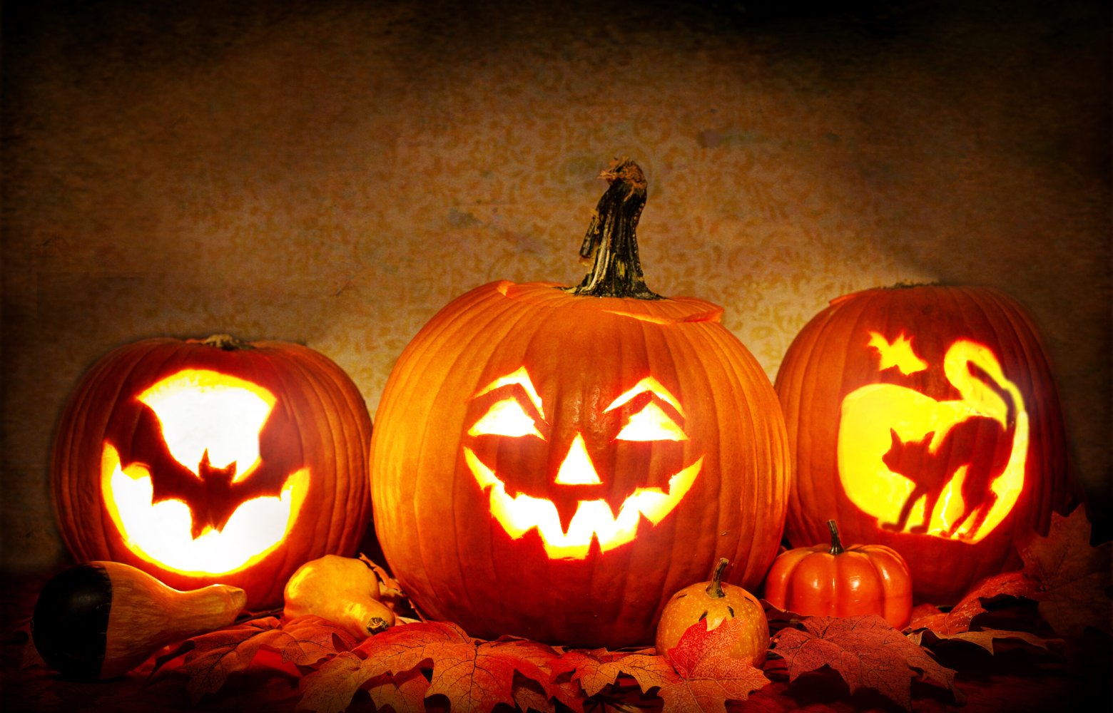 Three pumpkins decorated with Halloween designs, showcasing festive and spooky seasonal artistry.