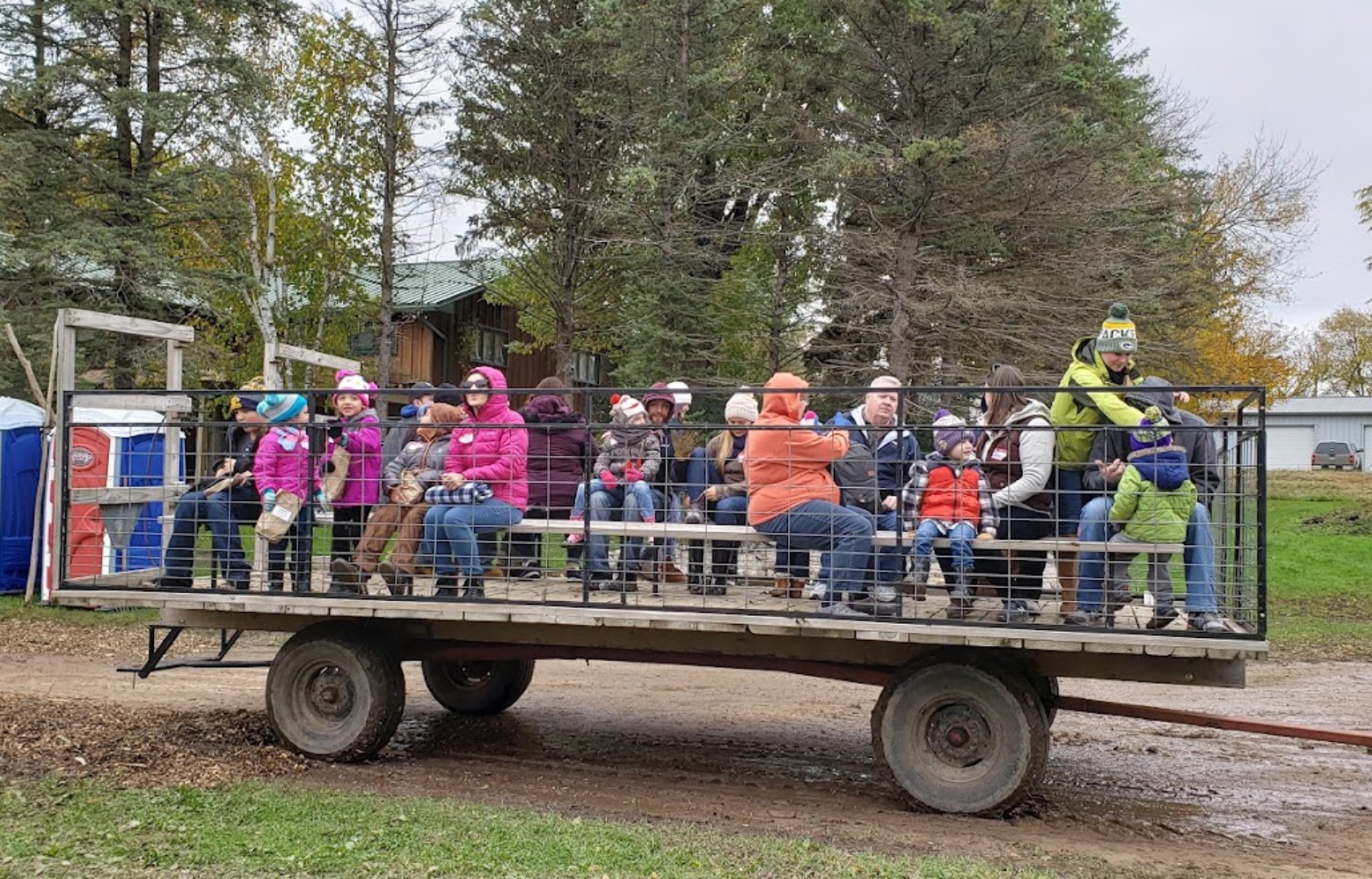 A lively scene of people seated on a traditional hay wagon, ready to embark on their hay ride adventure at Cavanaugh Carriages in Neenah, WI.