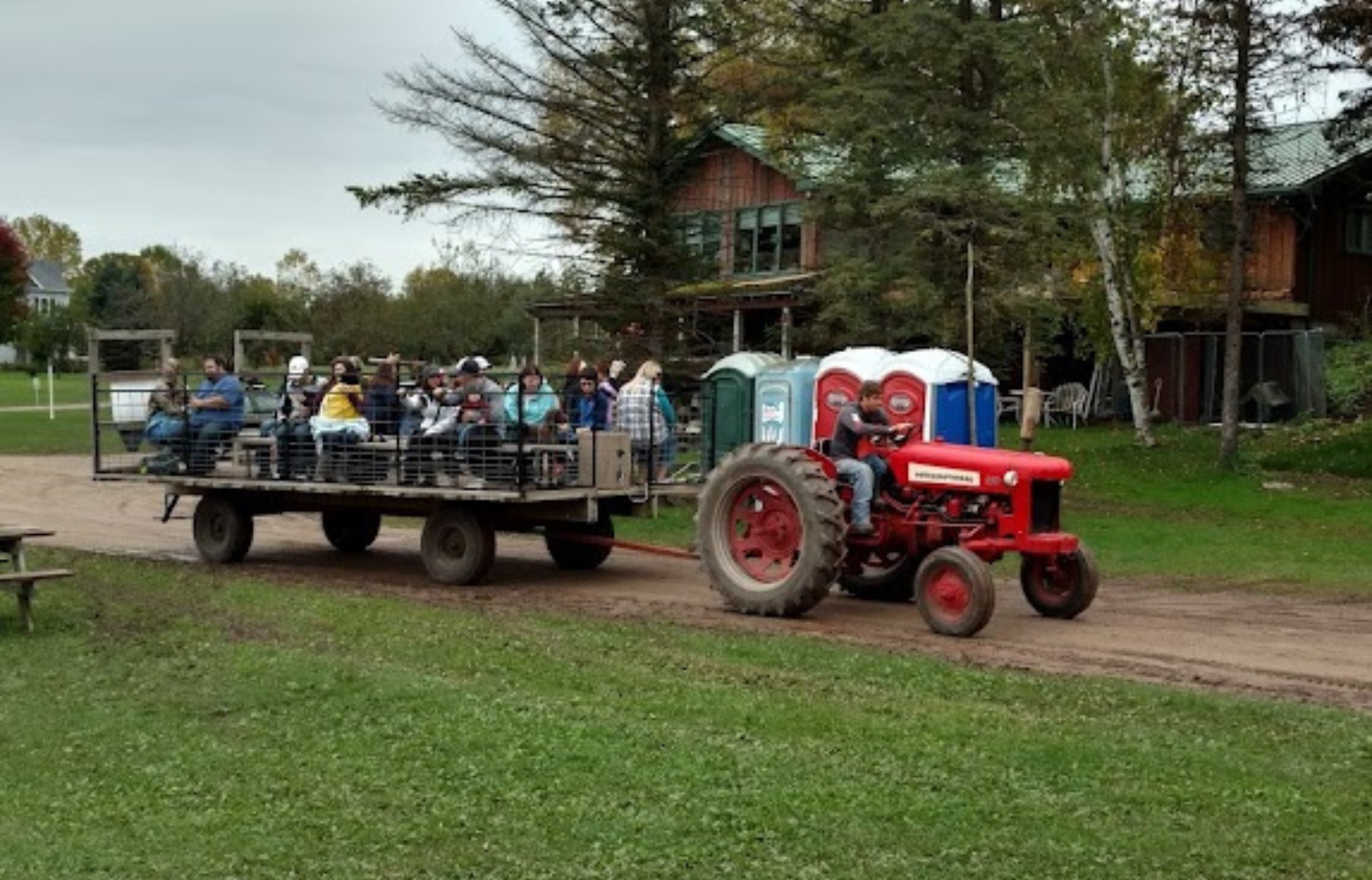 A group of smiling individuals seated on a hay ride wagon, setting off on their scenic hay ride adventure with Cavanaugh Carriages in Neenah, WI.