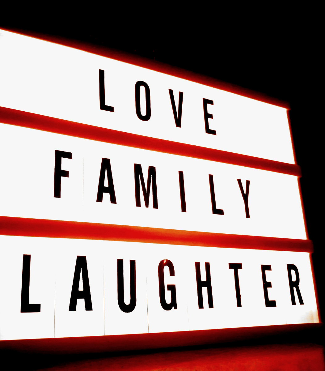 A decorative sign reading 'Love, Family, Laughter,' symbolizing the warmth and joy of family reunions hosted by Cavanaugh Carriages