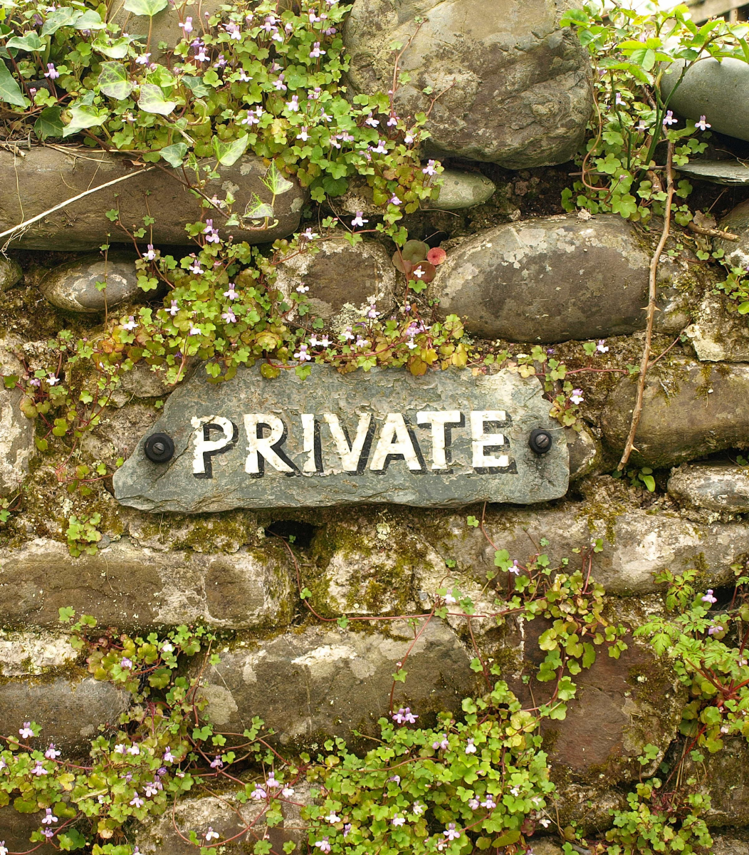 A stone wall with a 'Private' sign hanging on it, symbolizing the exclusivity and intimate atmosphere of private parties hosted by Cavanaugh Carriages