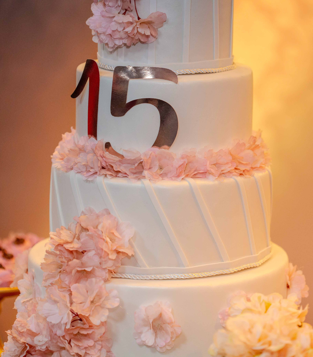 A beautifully decorated quinceañera cake celebrating a 15th birthday, symbolizing elegance and tradition for Cavanaugh Carriages' special events