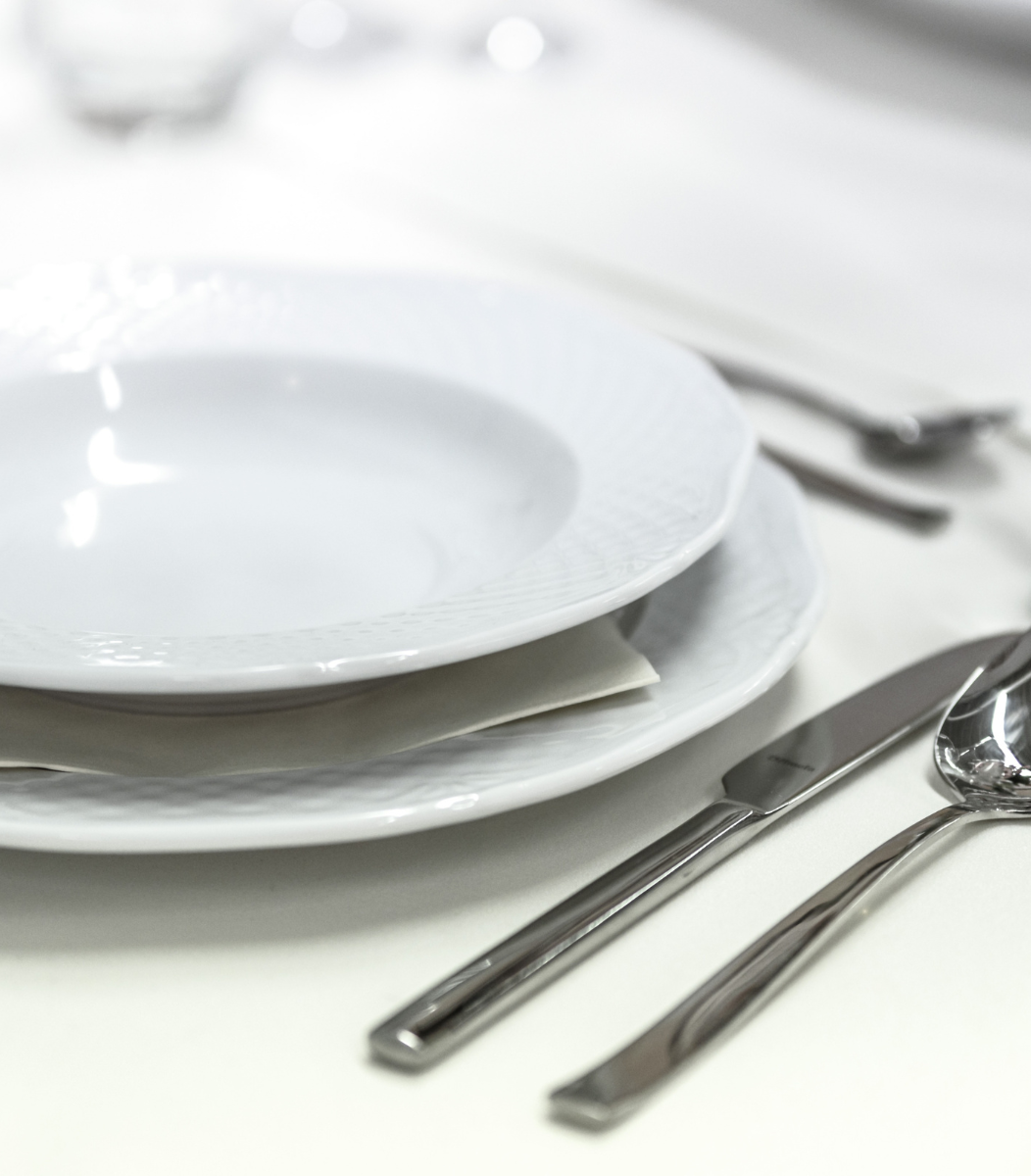 An elegantly set table with fine dining plates, silverware, and decor, highlighting the sophistication of Cavanaugh Carriages' banquet services