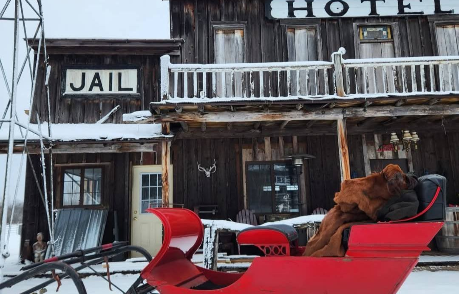 An empty sleigh parked near a classic hotel-themed building, ready to be boarded for a scenic winter ride.